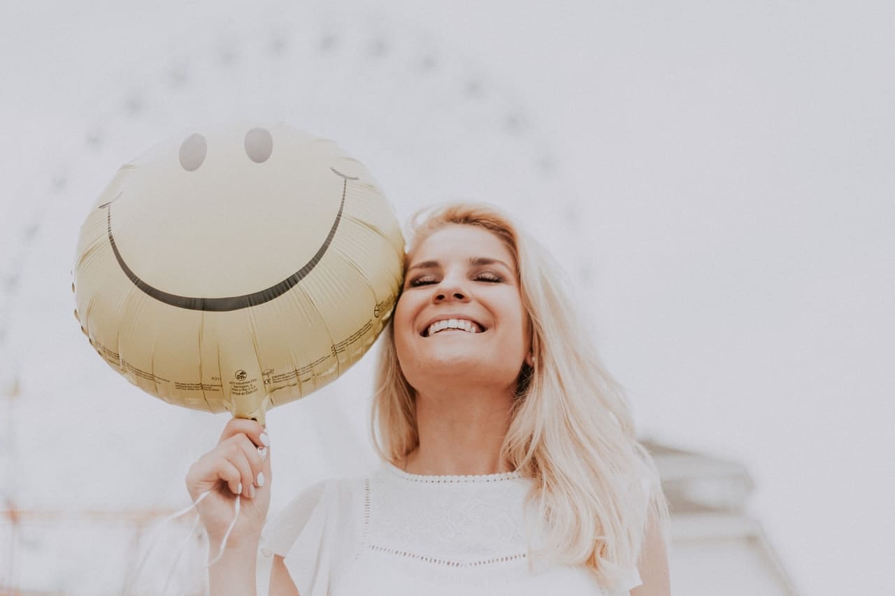 happy woman holding a smiley ballon